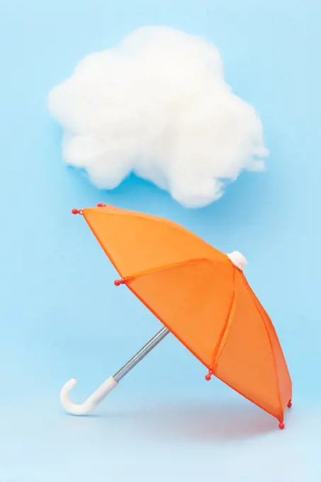 Orange Umbrella on Blue Background with Fluffy Clouds Spring