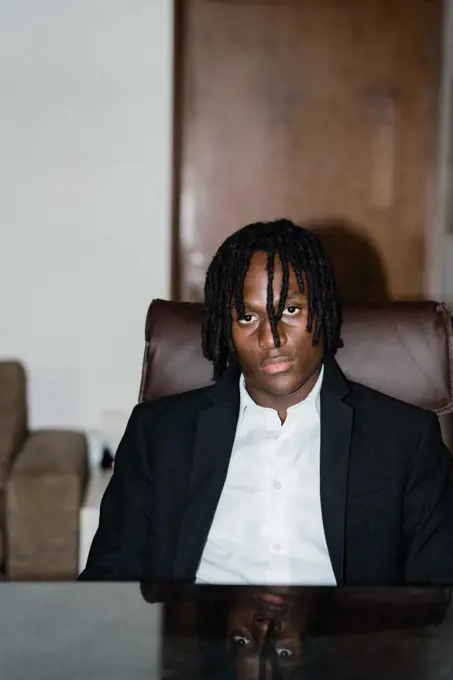 Portrait of the black man with dreadlocks wearing a suit sitting