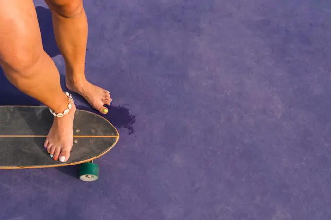 Woman with colorful toe nails standing on her skateboard on the 