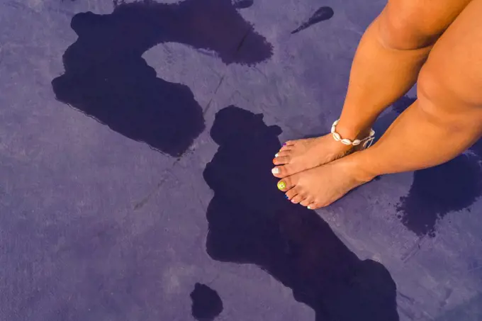 Woman with colorful toe nails standing on the purple background 
