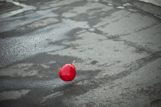 Red ball flies over asphalt. Balloon outside.