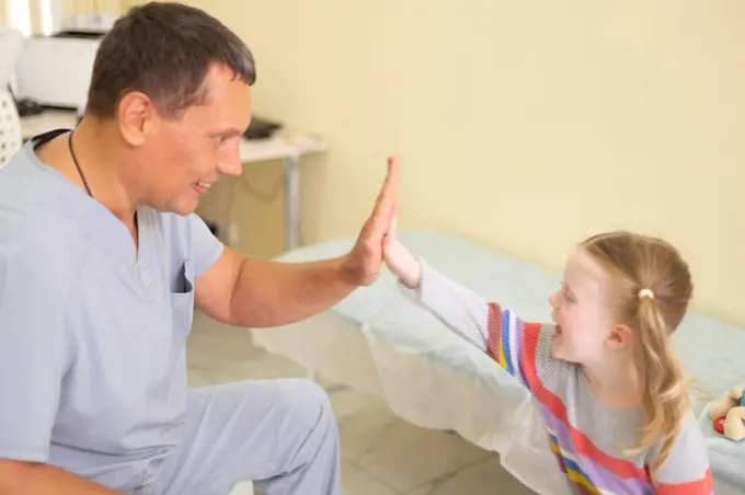 4 year old patient joyfully high fives to the male doctor