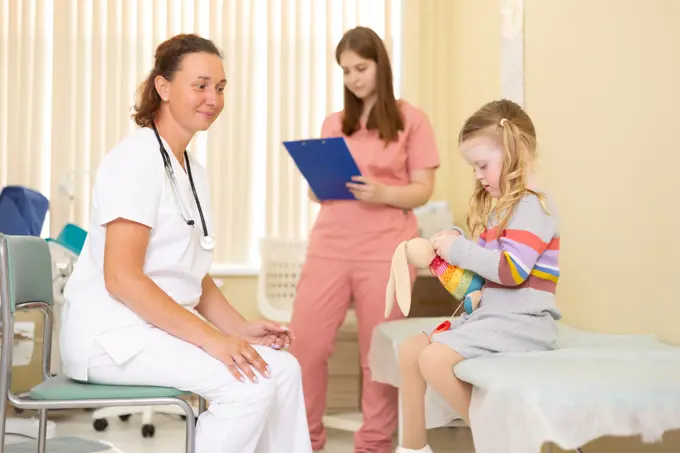 Doctor and nurse chatting with little girl in doctor's office