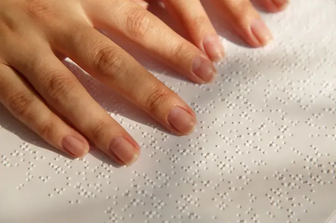 Woman's fingers on a book page with braille