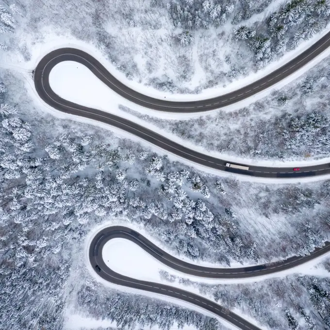 Winter snow winding road Serpentine Switchbacks forest woods season aerial photo view square drone