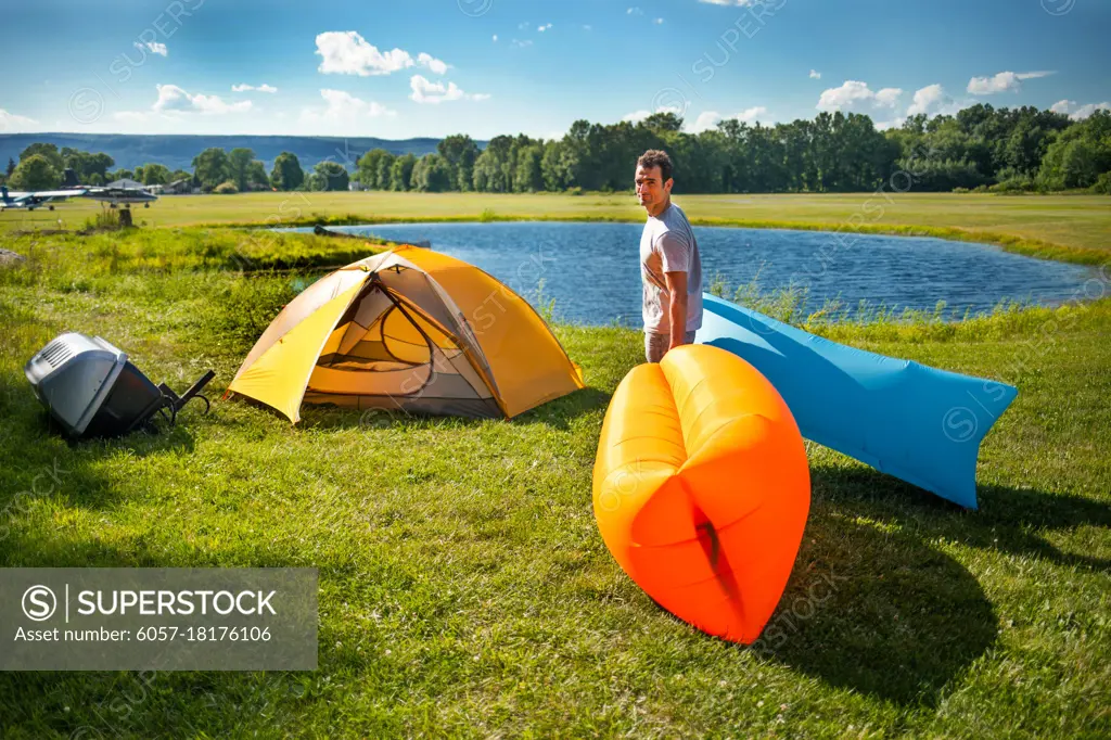 Man setting up Inflatable sofas out in the wild camping in summer