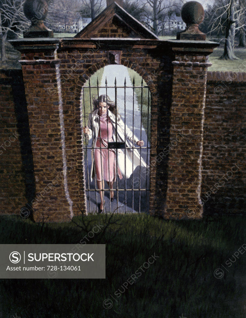 Stock Photo: 728-134061 Woman standing behind an iron gate