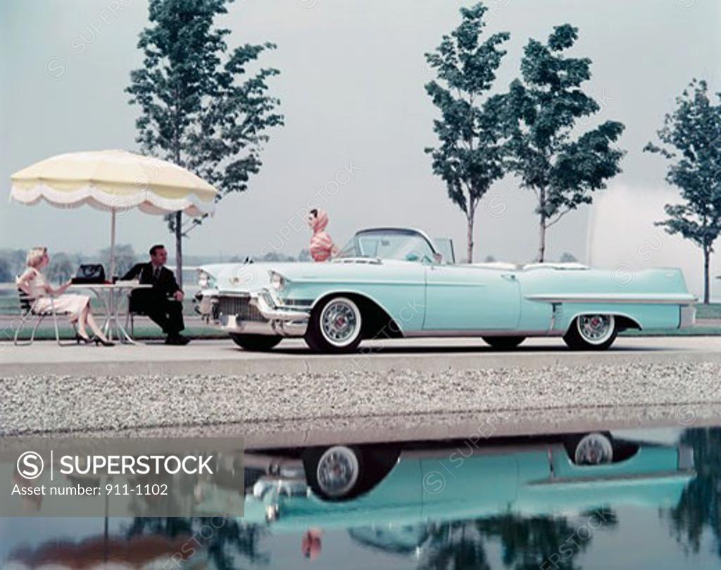 Stock Photo: 911-1102 Side profile of a mid adult woman standing beside a 1957 Cadillac convertible