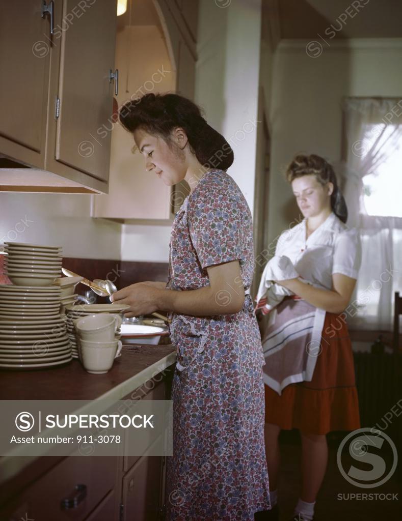 Stock Photo: 911-3078 Side profile of a mother working in the kitchen with her daughter