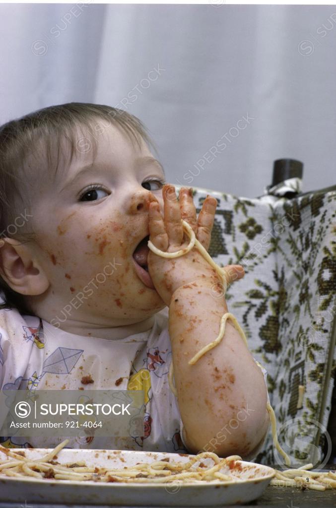 Stock Photo: 921-4064 Baby girl having a messy meal in a high chair